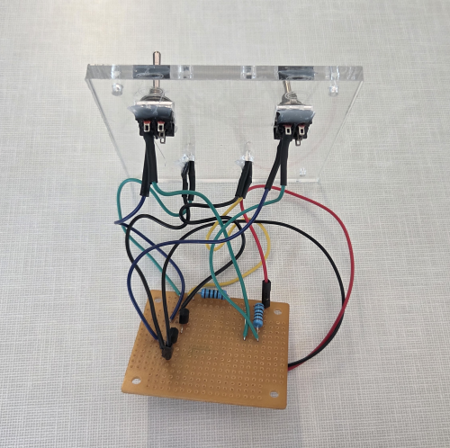 The NAND gate circuit described above, on a physical circuit board, connected to switches on an acrylic panel.